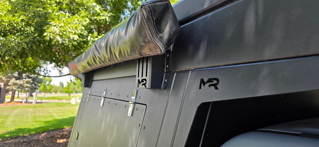 Close-up of a vehicle roof rack system with a brand logo on a grassy area.