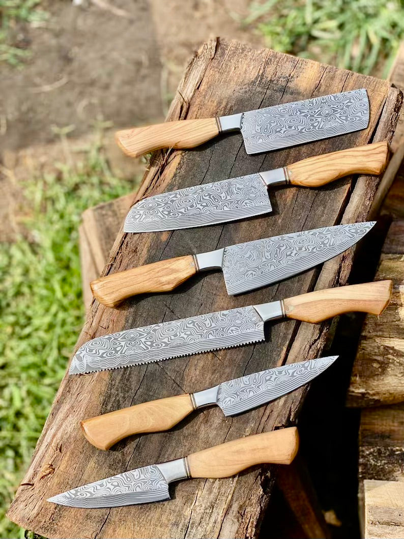 Set of six Damascus steel knives with wooden handles on a wooden block outdoors.