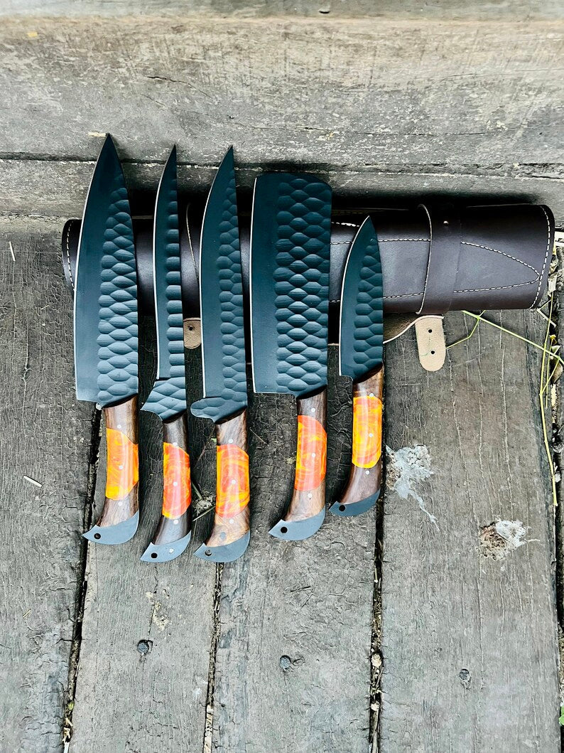 Set of five knives with black handles and orange blade tips on a wooden surface