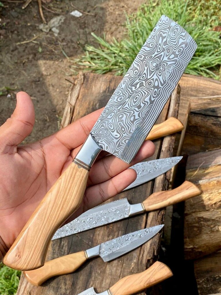 Set of Damascus steel knives with wooden handles on a wooden surface.