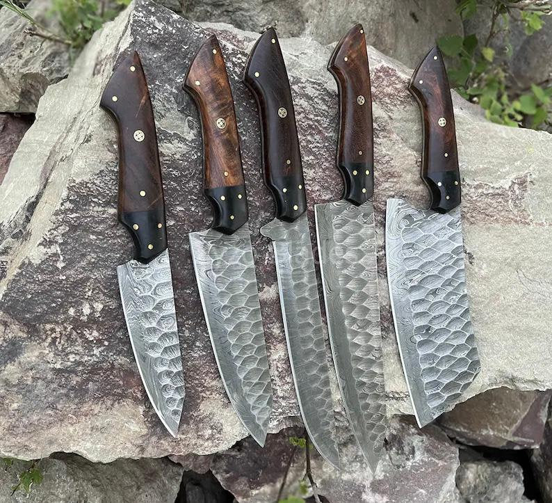 Set of five knives with wooden handles on a stone surface