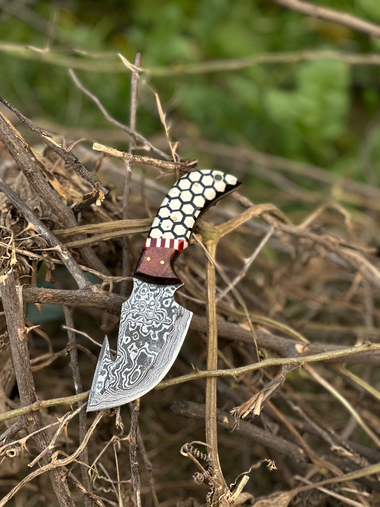Decorative knife with a detailed blade and textured handle on dry twigs