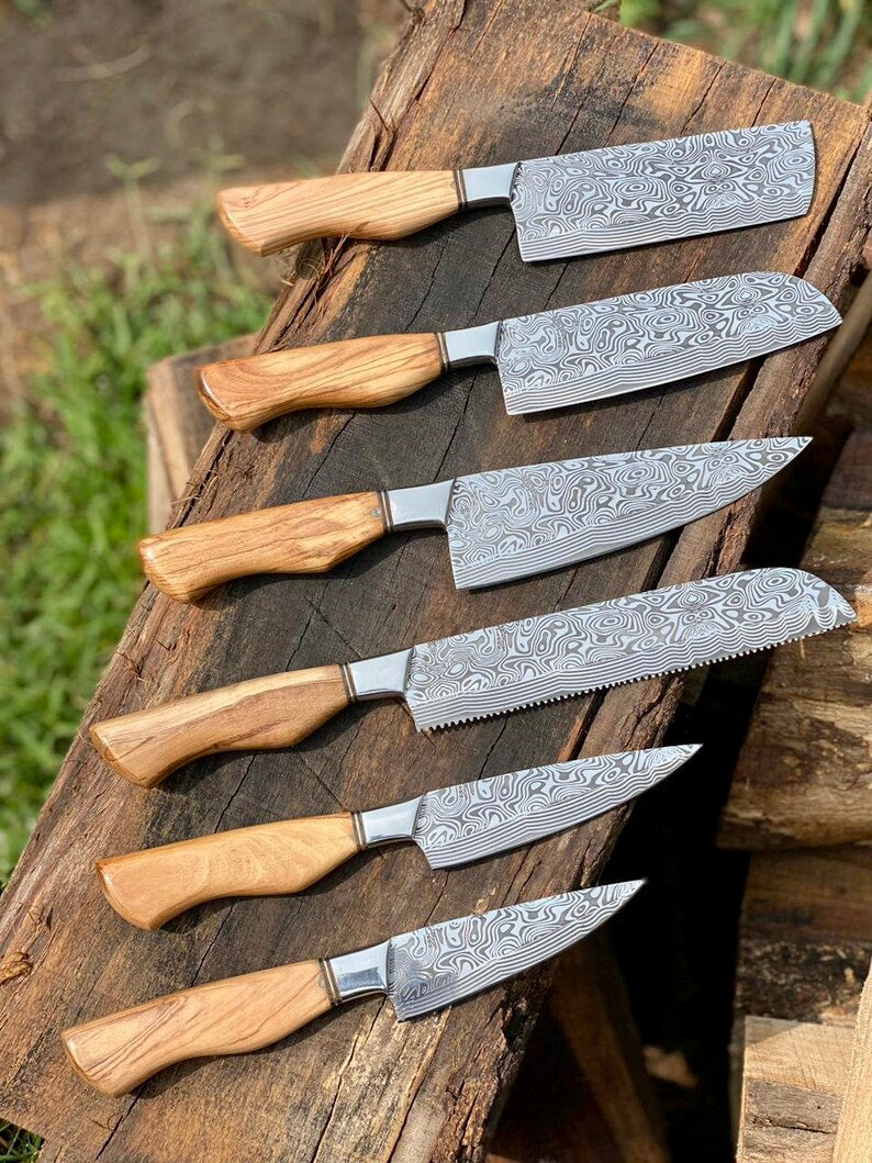 Set of six Damascus steel knives with wooden handles on a wooden surface.
