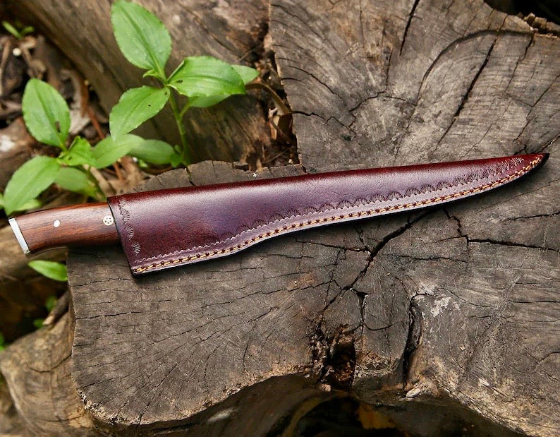 Leather knife sheath on a wooden surface with greenery