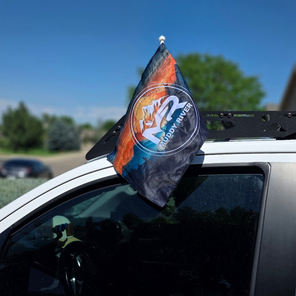 Muddy River flag mounted on a vehicle roof rack waving outdoors in the wind.