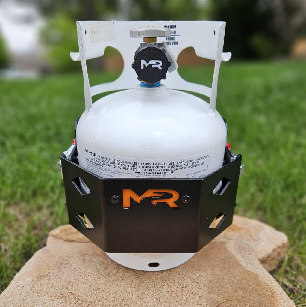Propane tank with a black and orange MR logo on a rock outdoors.