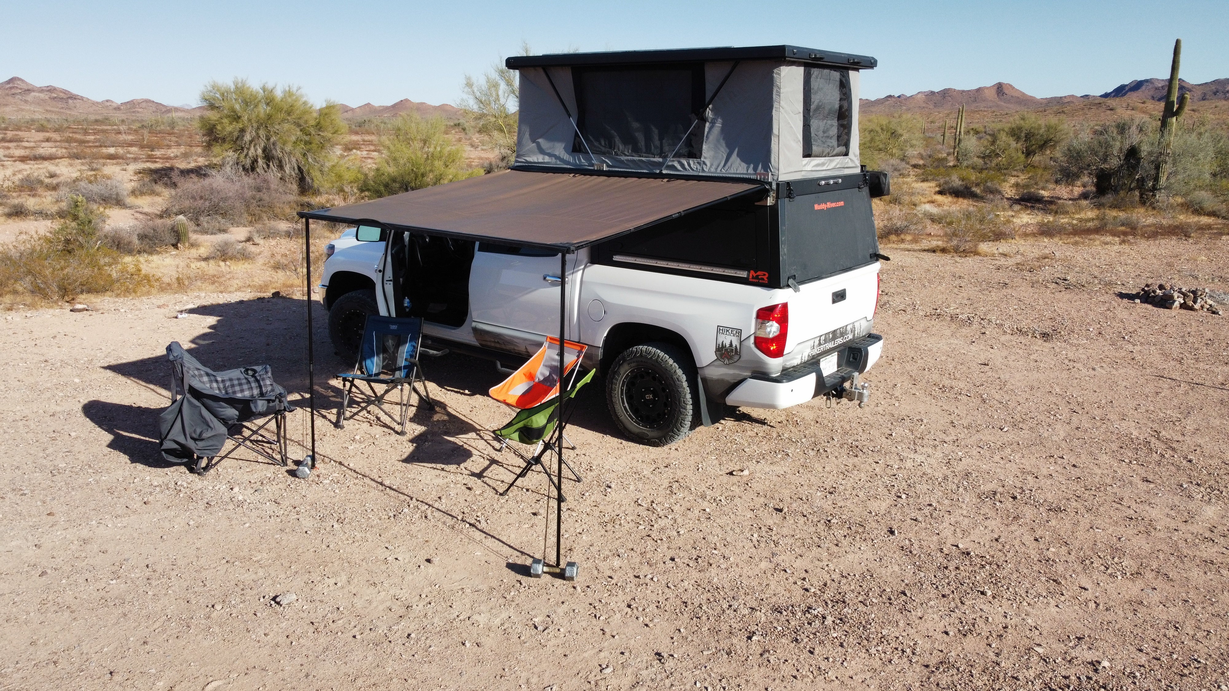 Camper truck with rooftop tent in a desert setting