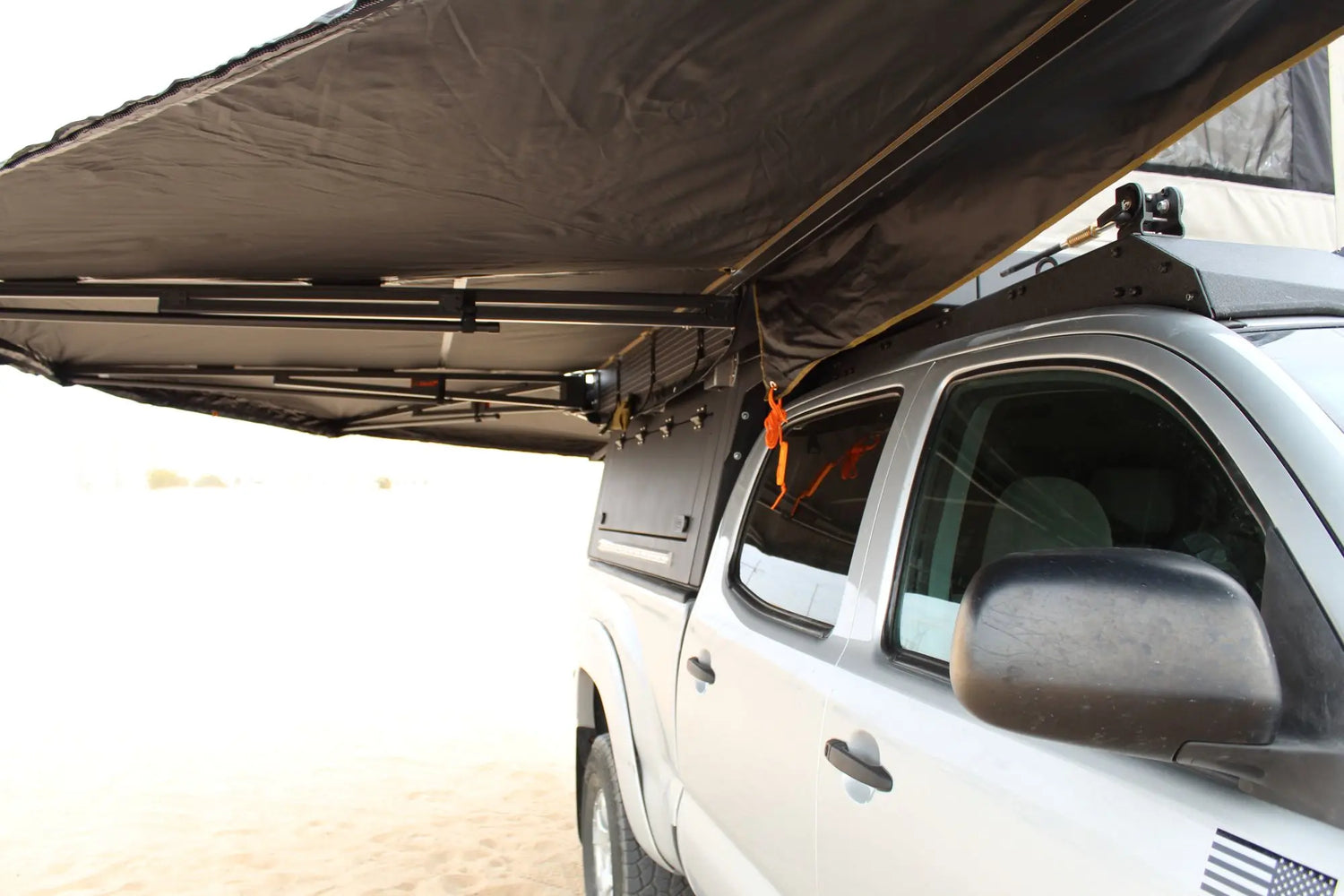Close-up view of an extended awning attached to a truck’s aluminum camper topper highlighting design and functionality for overland camping.