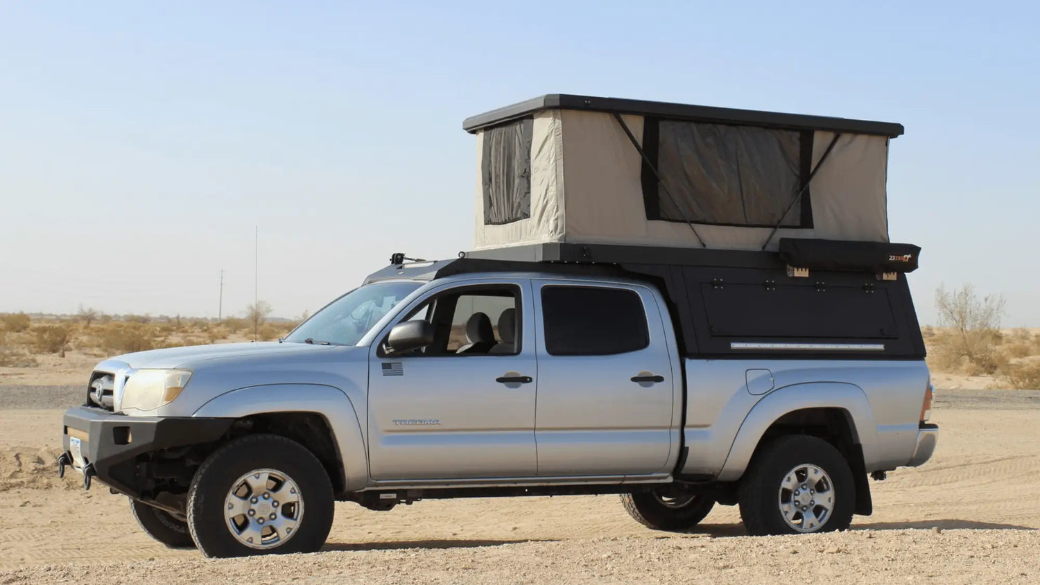 Camper Topper vs Truck Cap seasonal performance example with pop-up camper topper mounted on silver pickup truck in dry climate