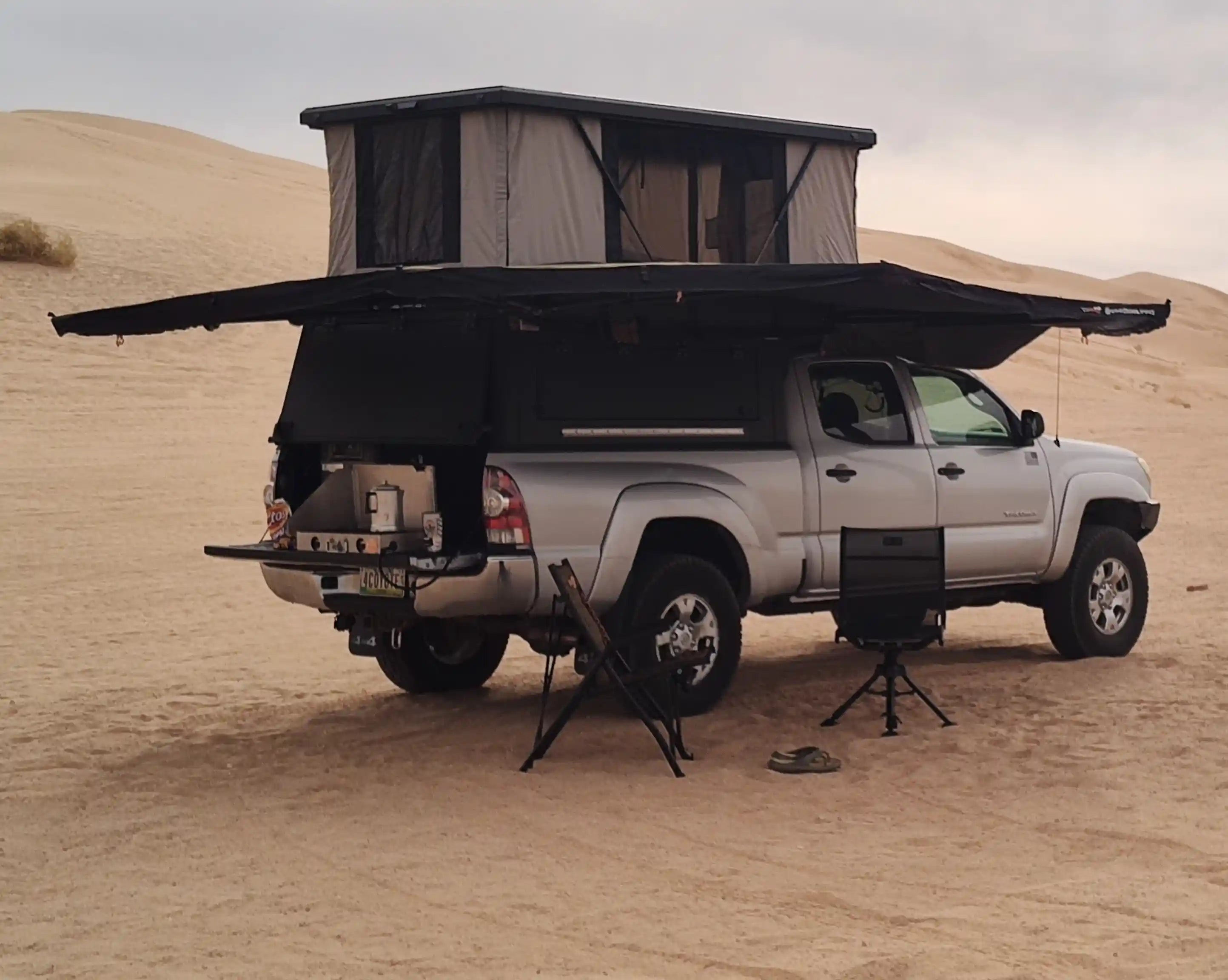 Truck camper setup in desert with awning extended and outdoor kitchen gear shown, part of truck camper buying guide for off-grid camping.