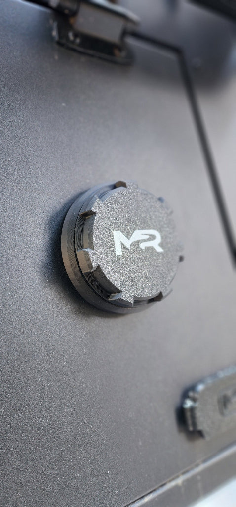 Mounted diesel / Propex heater port with textured cap on the exterior wall of an off-road camper topper.