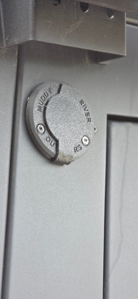Power Plug Mount and Cover installed on exterior camper panel with Muddy River Outdoors branding.