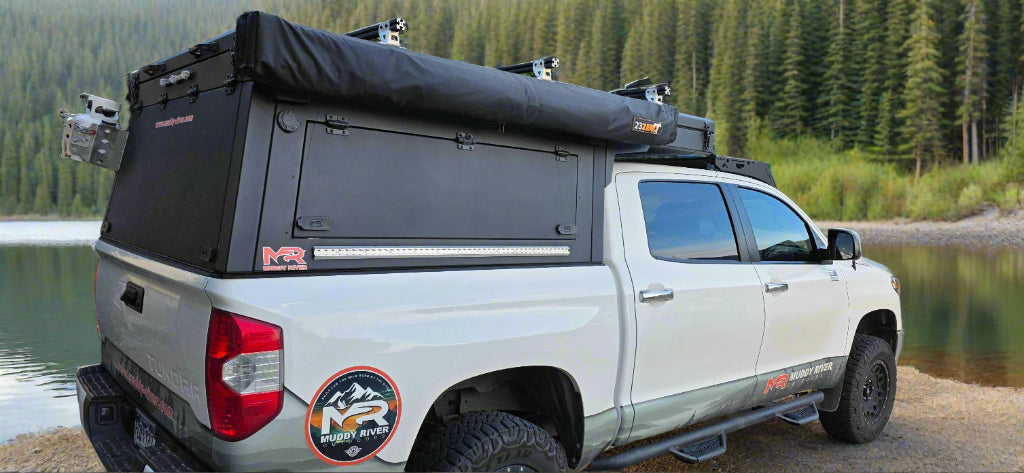 2nd Gen Toyota Tundra with an Eddy Camper Topper installed with a stream and pine tree in the background
