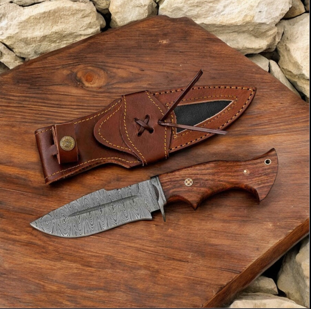 Knife with wooden handle and leather sheath on a wooden surface with stone background
