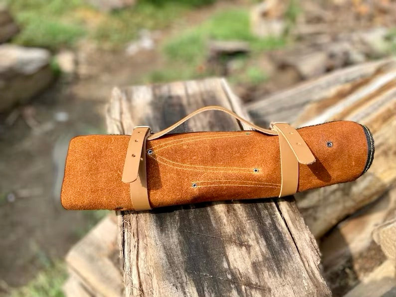 Brown leather-bound book or notebook on a wooden log with a natural outdoor background