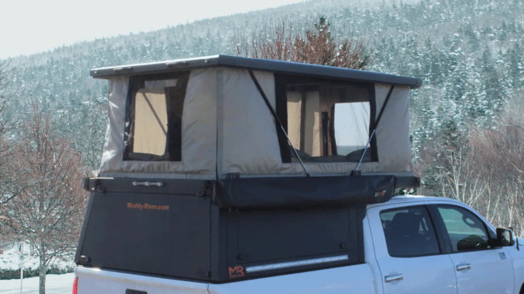 White truck with a rooftop tent in a snowy landscape