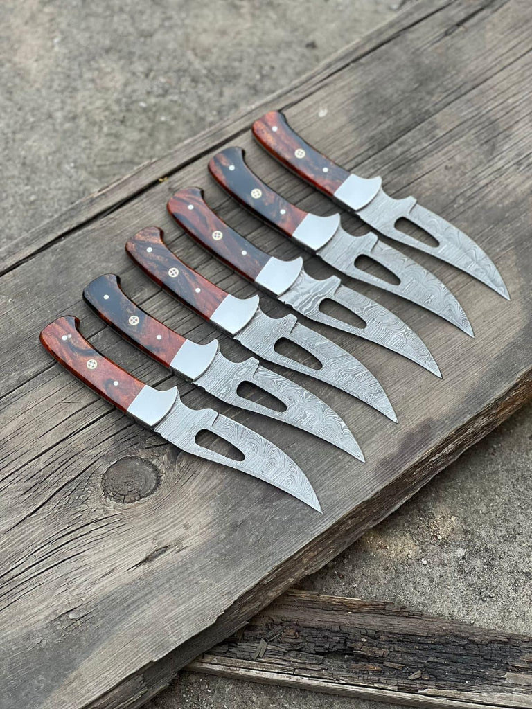 Set of six knives with red and brown handles on a wooden surface