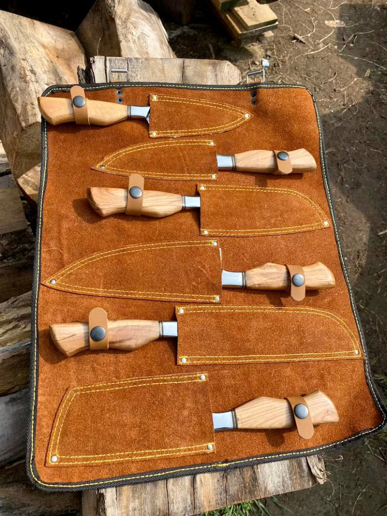 Set of wood carving tools in a brown leather case on a wooden surface.