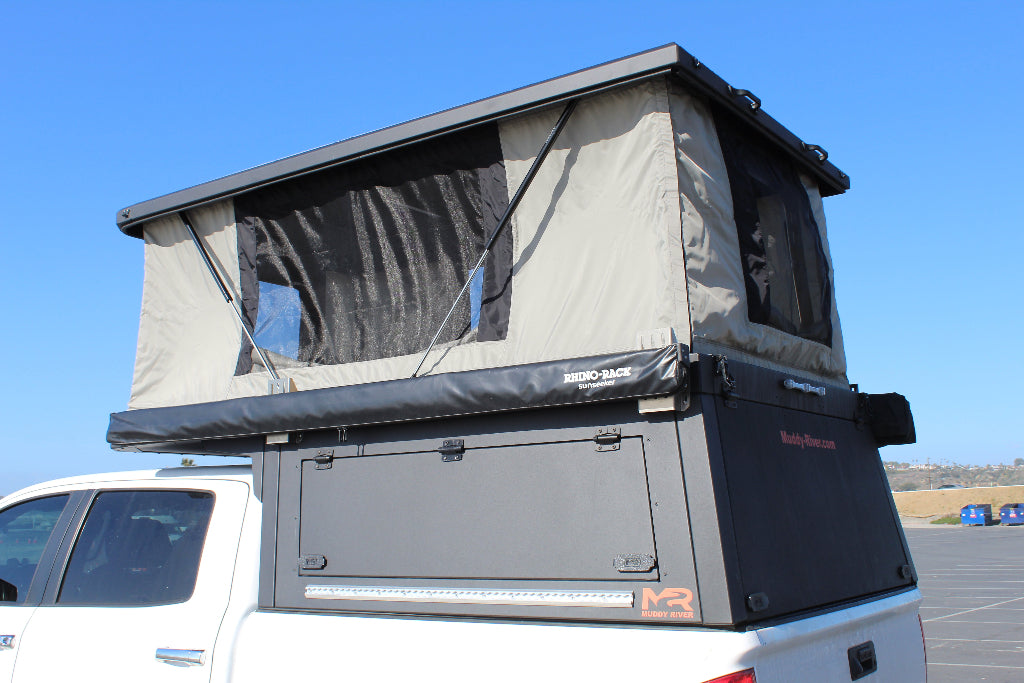 Camper tent attached to a vehicle with a clear blue sky background