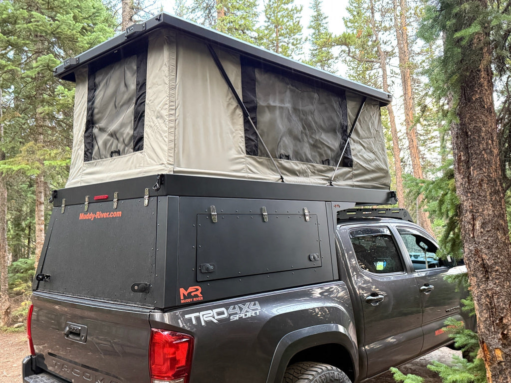 Gray truck with a rooftop tent in a forest setting