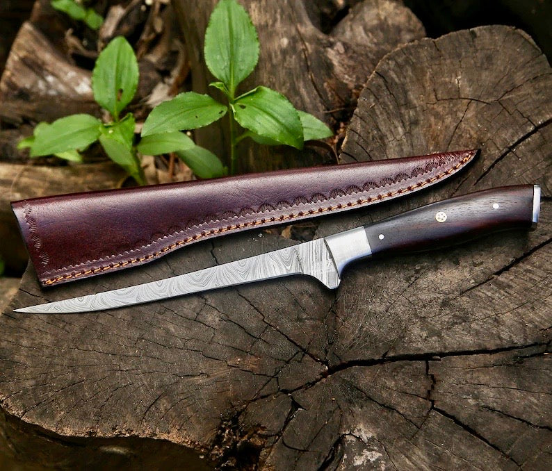 Knife with a leather sheath on a wooden surface with green plants in the background